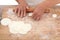 The chef rolls the dumpling wrapper on the cutting board with a rolling pin in hand