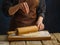 The chef rolls out floured dough on a wooden table with a rolling pin. Levitation. Dark background. Recipes for dough products -