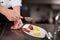 Chef\'s Hand Sieving Coco Powder In Plate At Kitchen Counter