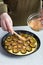 The chef`s hand sprinkles brown sugar on a raw plum cake in a baking dish