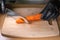 Chef& x27;s hands in black gloves holding a knife and cutting peeled cooked carrots on a kitchen wooden board