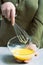 The chef`s hands hold the whipped butter in a glass bowl and a whisk over a light table