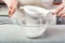 The chef`s hands sift the flour through a sieve into a glass container