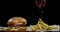 The chef is salting the French fries. Close up shot of delicious hamburger and fries.