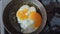 Chef seasons a frying egg, sunny side up, with ground pepper in a small frying pan over an industrial gas burning stove