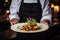 Chef serving a dish with artistic presentation, adorned with flowers and sauce