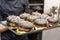 Chef showing a tray full of classic burgers with black buns