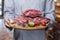 Chef shows on a wooden tray meat packed in a vacuum on the background of a cafe