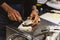 Chef shucking a fresh oyster by knife on stainless steel counter bar