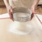 Chef sifting baking powder into dough