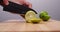 Chef sliced green lime with knife on wood cutting board table.