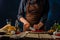 The chef slices tomatoes for the classic Caesar salad. Lots of ingredients. Wooden structure. Dark blue background. Detailed