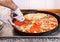 Chef slicing a pizza with four assorted toppings