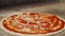 Chef spreading tomato sauce on pizza dough