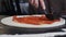 Chef spreading Tomato Sauce on Pizza Dough with Ladle in Traditional Italian Pizza restaurant. Slow motion food video