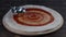 Chef spreading tomato sauce on pizza dough with metal ladle in pizza restaurant