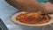 Chef spreads tomato paste on italian pizza
