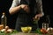 The chef sprinkles with greens, spiced rosemary french fries, on the background with vegetables. Cooking tasty but harmful food.