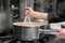 Chef stirring sauce in stainless steel pot, close-up. Professional kitchen, restaurant.