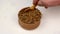 Chef taking dry coriander seeds or chinese parsley spices from wooden spice jar. Close-up.