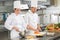 Chef teaching colleague how to slice vegetables in kitchen