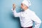 Chef trying meal. Confident mature chef in white uniform trying eating from wooden spoon and standing against blue