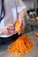 Chef in uniform preparing fresh carrot batons