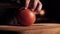 A chef with a very sharp knife cuts off a piece of tomato in one move. Close-up