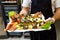 Chef or waiter holding platter full of fresh canapes finger food snacks for buffet meal at restaurant