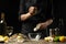 Chef watering raw oyster with lemon juice, with dry Italian wine, for cooking and cooking on a black background, Concept menu,