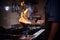 Chef wearing gloves and apron frying flambe on a pan in a dark restaurant kitchen