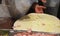 The chef in a white apron makes a huge pizza, close-up of pizza ingredients-ham, cheese, Dark background