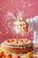 Chef in White Jacket Tossing Gourmet Pizza in Air with Flour Dust and Cheese Flying in Commercial Kitchen Setting