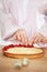 Chef Woman decorating cake with berries and cream cheese on kitchen table. Close-up of female hands making tartlet with