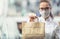 Chef woman in glasses and face mask hands over packed food for takeaway delivery