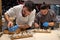 Chefs arranging appetizers on a wooden plate. Teamwork in kitchen.