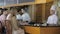 Chefs cook in white uniform for clients on the bar table at the open kitchen of the restaurant