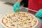 Chefs hand preparing pizza on kitchen table top with quail egg,