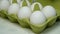 Chefs hand in rubber protective gloves take two white chicken eggs from cardboard eggs tray for cooking breakfast