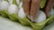 Chefs hand in rubber protective gloves take two white chicken eggs from cardboard eggs tray for cooking breakfast