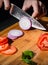 Chefs hands chopping onion on wooden board