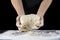 Chefs hands knead the dough on a dark table. The concept of baking and pastry