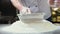 Chefs hands throws the flour through a sieve