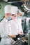 Chefs in protective masks and gloves prepare food in the kitchen of a restaurant or hotel.