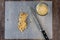 Chefâ€™s knife and a pile of partially chopped raw walnuts on a plastic cutting mat, small glass bowl with chopped nuts