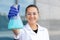 A chemical conical flask with a blue liquid held by a white-skinned girl scientist in a white coat, goggles