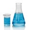 A chemical flask, beaker with blue liquids and sheet of paper wi