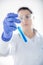 Chemist`s hand on white background holding test tube with blue liquid