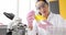 Chemist scientist in protective rubber gloves holds flask with yellow liquid closeup