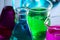 Chemistry laboratory beakers a containing pink , blue and green solutions on a reflecting surface